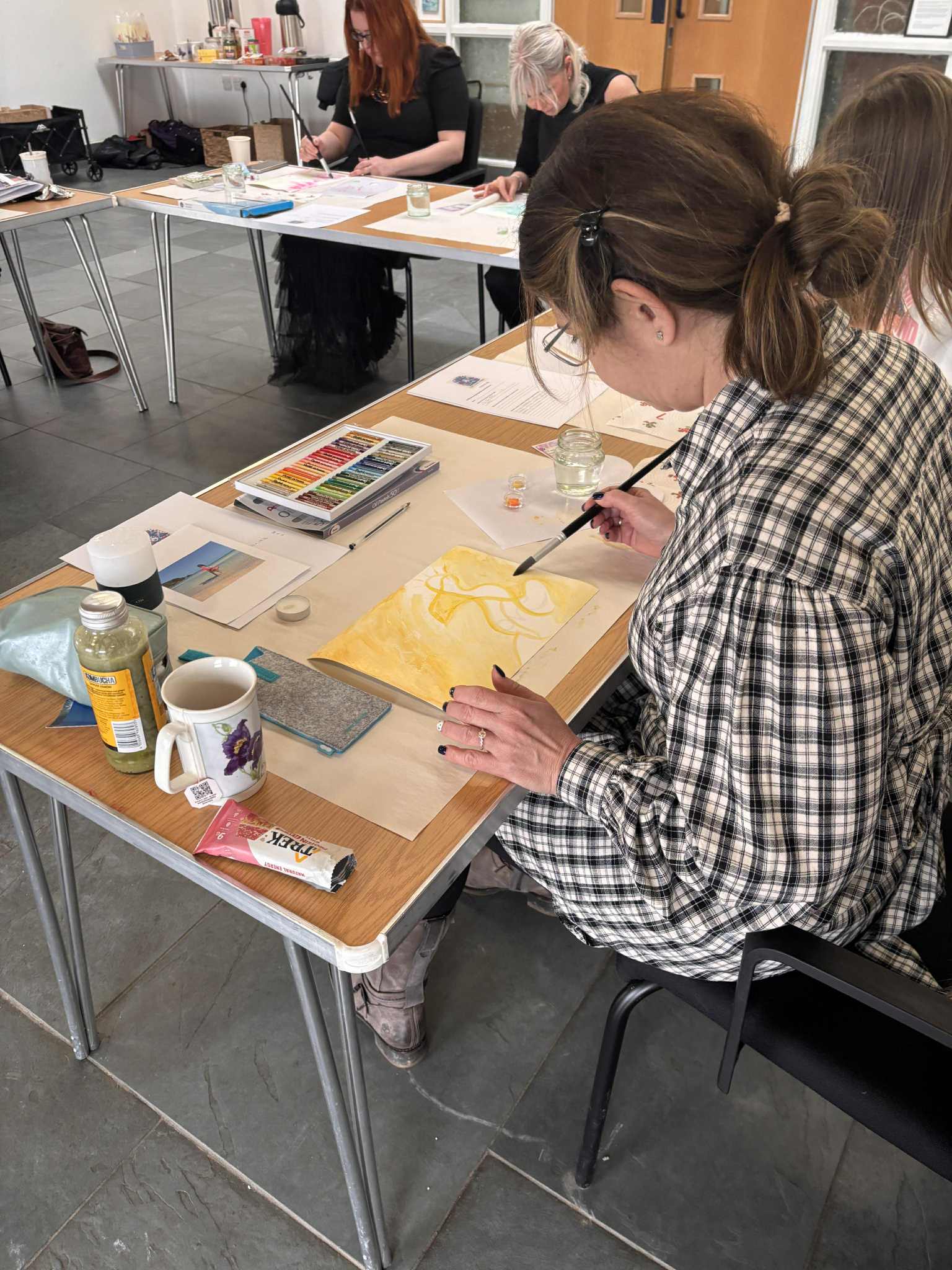 Lady at workshop table with paints and materials on it - future workshops will look like this
